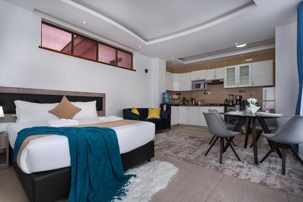 Una moderna camera d'albergo con un letto, un'area pranzo e un angolo cottura.