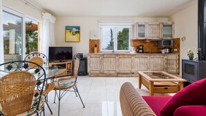 A spacious living area with a glass dining table, wicker chairs, a red sofa, and a kitchen with wooden cabinets and a microwave. - A detached vacation home with country house charm (CN)