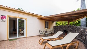 A patio with two sun loungers, a table with chairs, and a small covered area. - A detached vacation home with country house charm (CN)