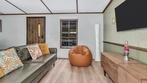 A modern living room with a sofa, bean bag, and a flat-screen TV.