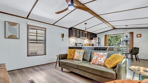 A modern living room with a sofa, a dining area, and a kitchen in the background.