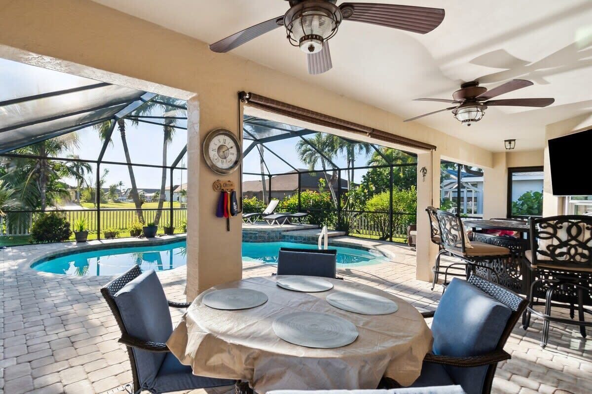 Une terrasse extérieure avec une piscine, un espace salon couvert et un coin repas.