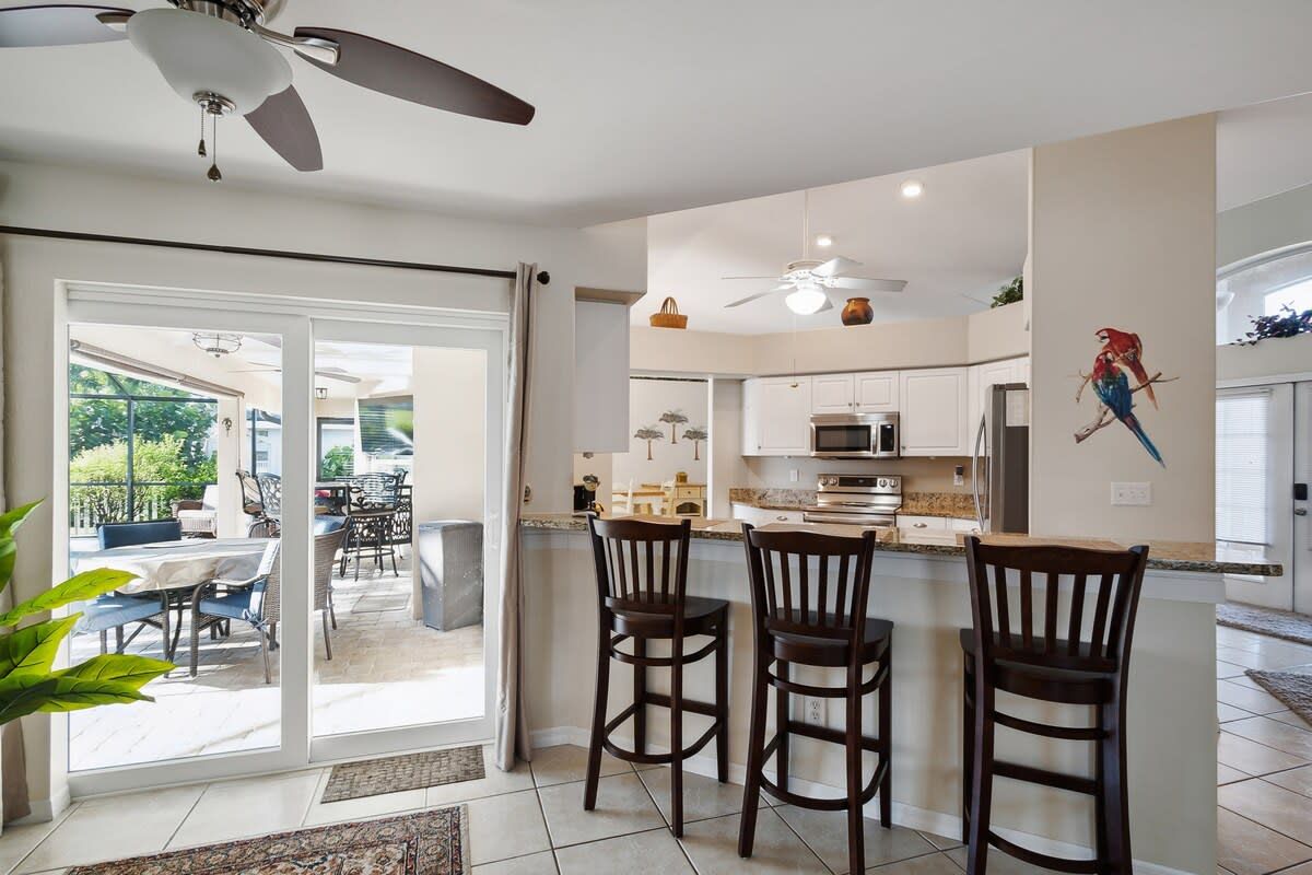 A modern kitchen with a bar area, sliding glass doors leading to an outdoor patio, and a ceiling fan.