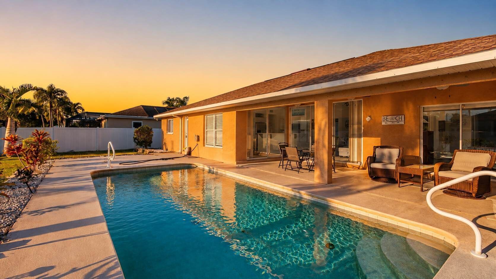 A swimming pool with a lounge area, a covered patio, and a building with a sign that reads 'BEACH'.