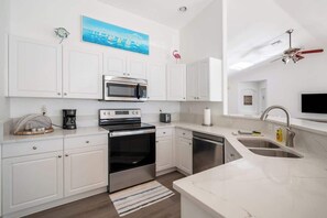 A modern kitchen with white cabinetry, a stainless steel oven, a microwave, and a sink.