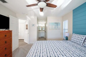 Un dormitorio con cama, cómoda, ventilador de techo, pintura y ventana con persianas.