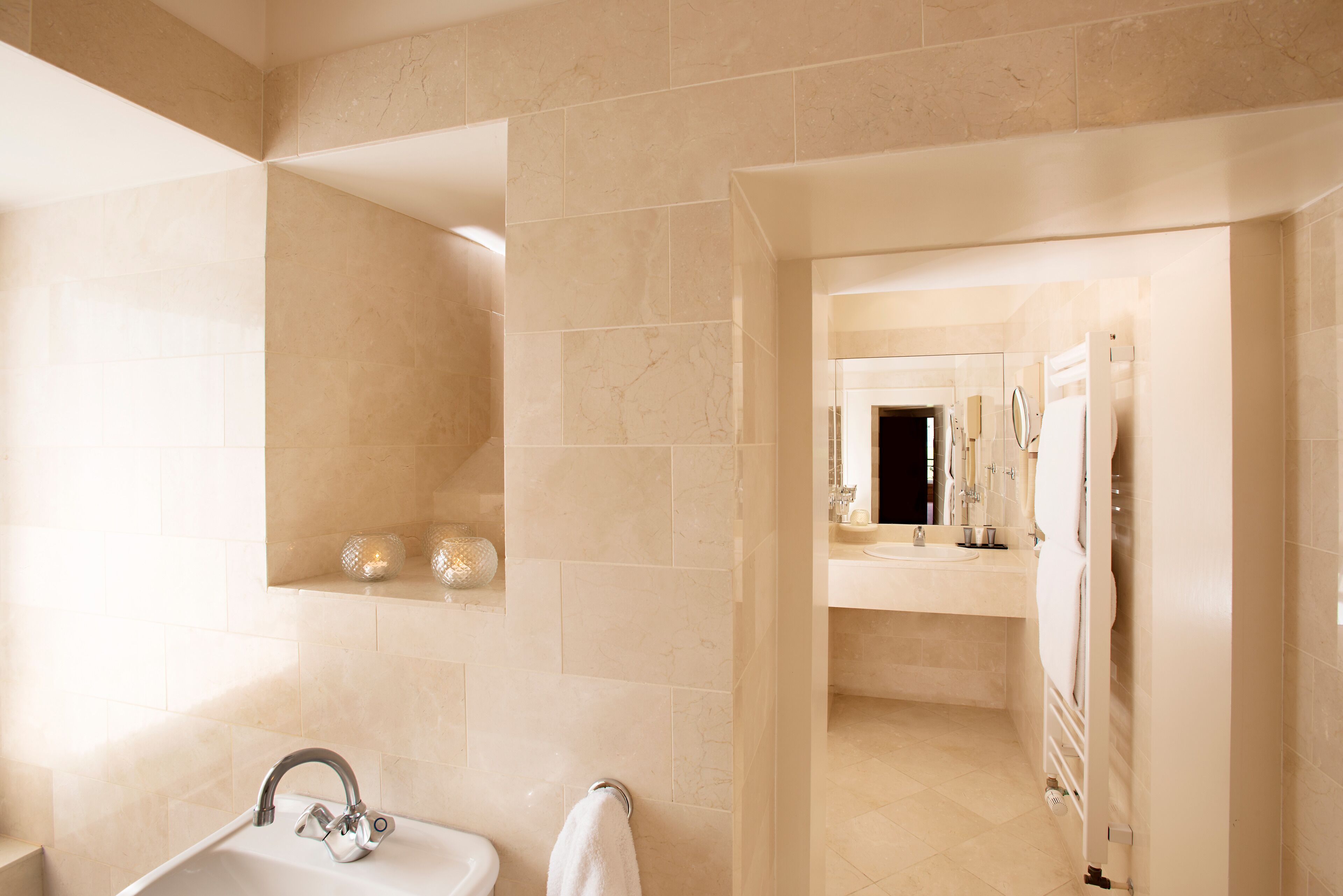 Un baño moderno con lavamanos, espejo y toallero.