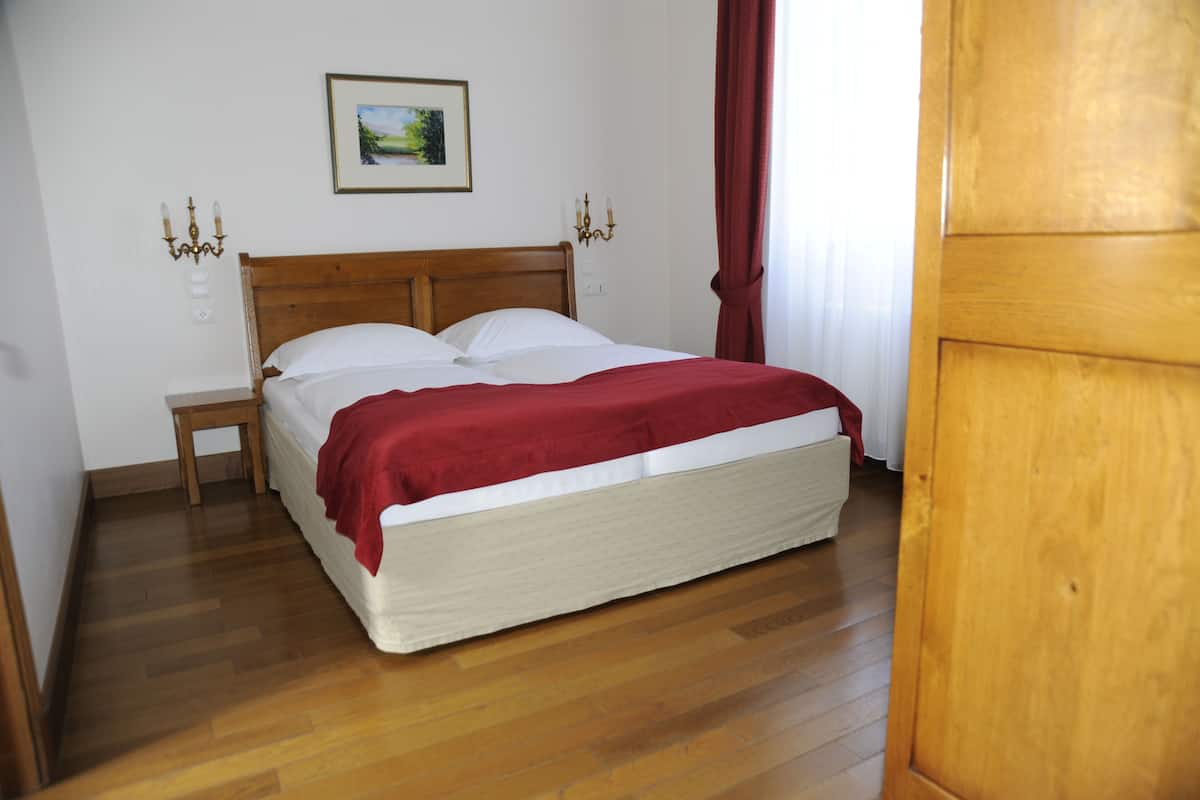 A neatly made bed with a wooden headboard, a small bedside table, and a wall-mounted picture.