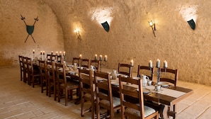 A dining room with a long table set for a meal, wooden chairs, and wall-mounted candle sconces. - Hapimag Château de Chabenet (Le Pont-Chretien-Chabenet)