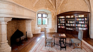 A library with a fireplace, bookshelves, and a chess table. - Hapimag Château de Chabenet (Le Pont-Chretien-Chabenet)