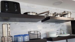 A modern kitchen with white tiled backsplash, stainless steel appliances, and black countertops. - Oceanfront Efficiency T604 (Myrtle Beach)