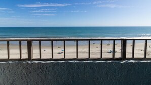 Ein Strand mit einer Holzbank im Vordergrund, feinem Sand und dem Meer im Hintergrund.