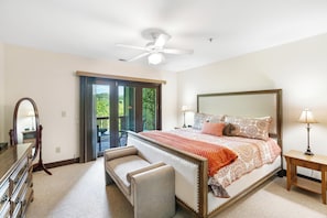 Een slaapkamer met een bed, een bankje, een dressoir, een spiegel, een plafondventilator en uitzicht door een schuifdeur.