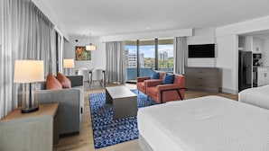 Et moderne hotelværelse med en stor seng, to sofaer, et spisebord og et tekøkken.