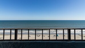 Blick auf einen Strand mit einem Geländer im Vordergrund.