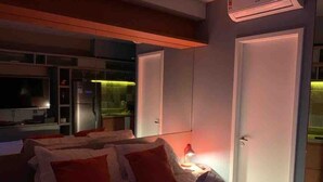 A bedroom with a bed, bedside tables, a mirror, and an air conditioning unit. - Luz 1802 (São Paulo)