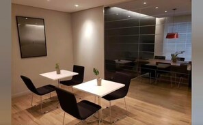 A modern conference room with a glass partition, wooden flooring, and black chairs. - Luz 1802 (São Paulo)