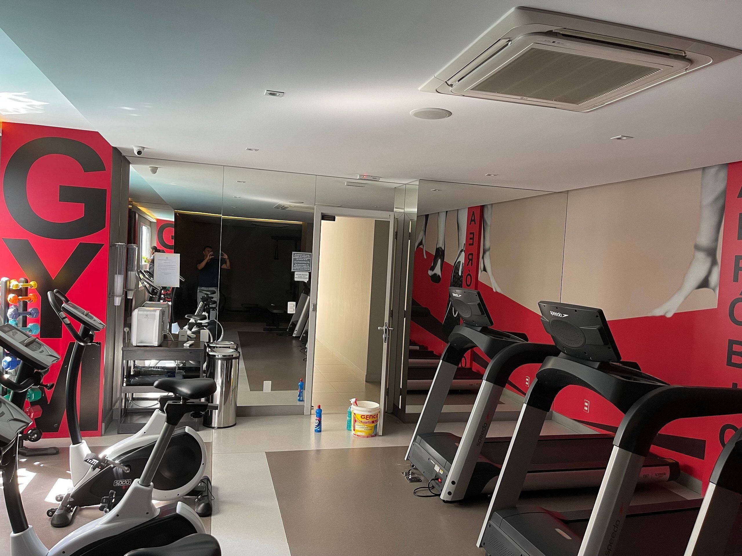 A gym with treadmills, stationary bikes, and a large 'GY' sign on the wall.