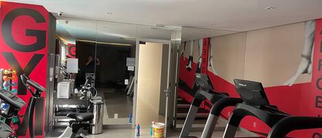 A gym with treadmills, stationary bikes, and a large 'GY' sign on the wall.