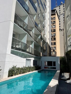 A modern building with a pool and outdoor seating. - Luz 1802 (São Paulo)