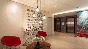 A modern interior with a motivational quote on the wall, a red chair, and a unique light fixture. - Luz 1802 (São Paulo)
