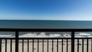 A beach view from a balcony with a railing, ocean waves, and a clear sky. - Experience Luxury Oceanfront Getaway10th Floor (Myrtle Beach)