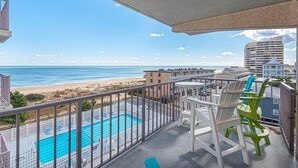 A balcony with a view of the beach and a swimming pool.