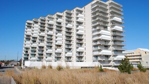 A multi-story residential building with balconies, a flat roof, and a clear sky.