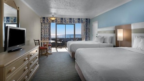 A hotel room with two beds, a TV, a desk with a chair, and a view of the sea. - Ocean Oasis 11th Floor Two Queen Oceanfront Room (Myrtle Beach)