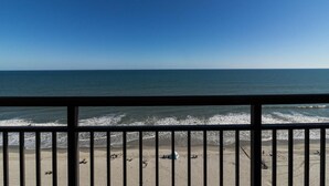 A beach view from a balcony with a railing, sandy beach, and ocean. - Embrace Coastal Living Oceanfront Room 11th Floor (Myrtle Beach)
