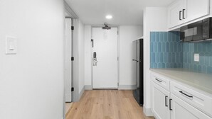 A narrow hallway with a wooden floor, white walls, and a door at the end. - Ocean Oasis 14th Floor Two Queen Oceanfront Room (Myrtle Beach)