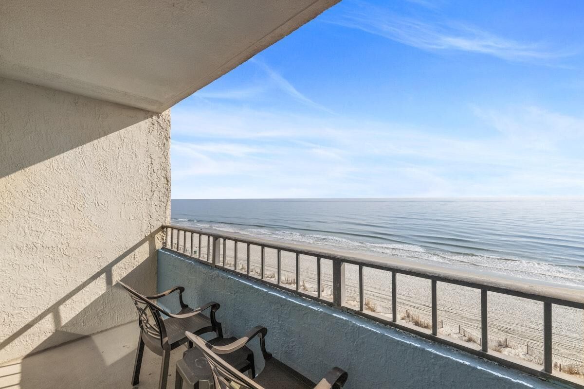 Ein Balkon mit Blick auf den Ozean, ausgestattet mit einem Geländer und einigen Stühlen.