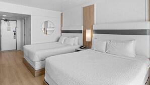 Ein Hotelzimmer mit zwei Betten, einer Holzwand, einem runden Spiegel und einem Nachttisch mit Lampe.