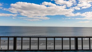 A beach with a wooden railing, calm sea, and a clear sky with clouds. - Seaside Charm Comfort Ocean Reef Resort 7th Floor (Myrtle Beach)