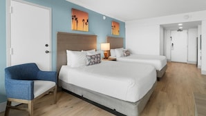 Una habitación de hotel con una cama grande, una silla y dos cuadros en la pared.