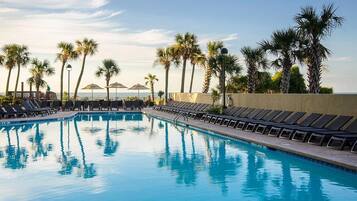 A swimming pool with lounge chairs and palm trees.