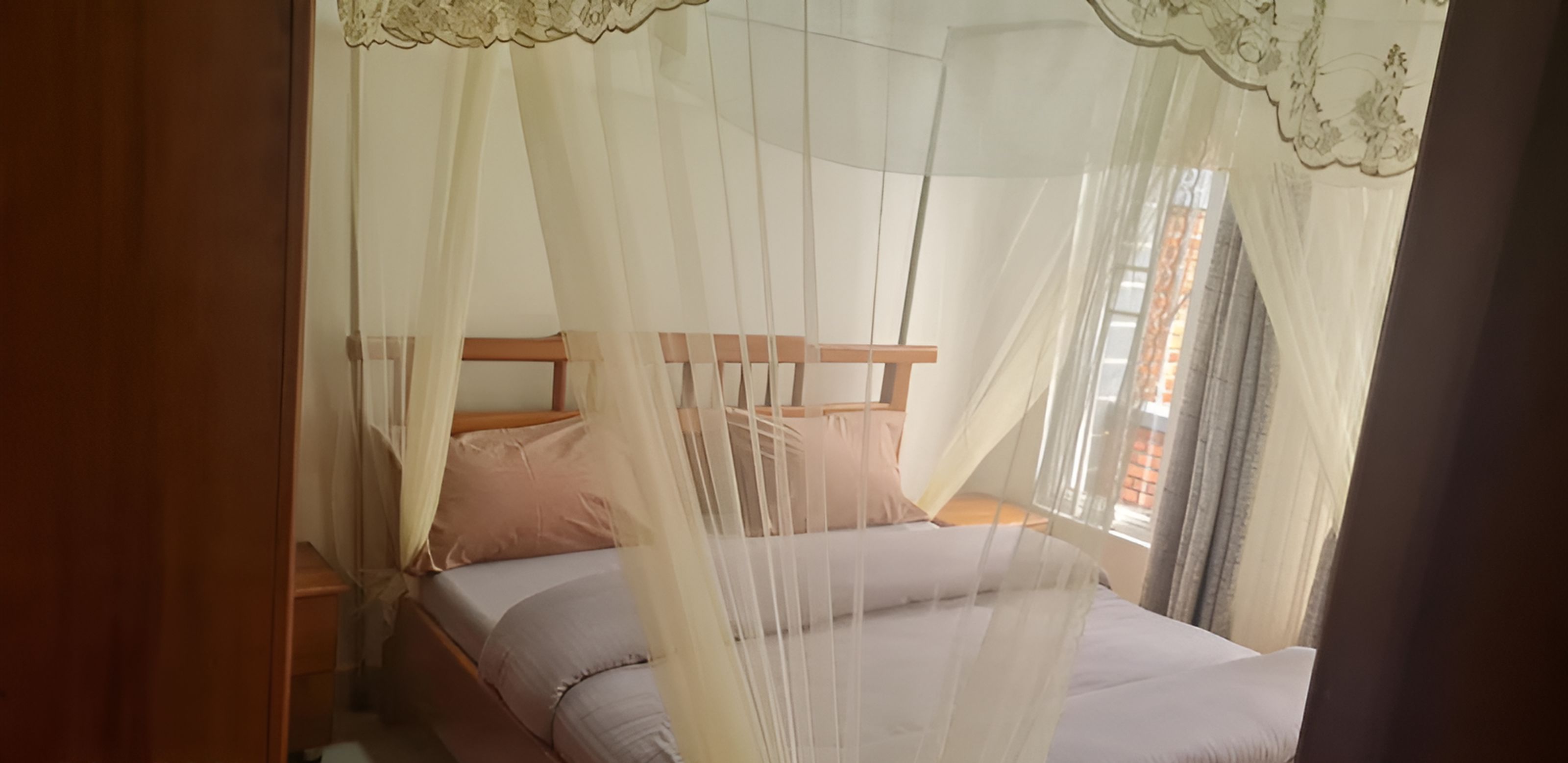 A bed with a canopy, wooden headboard, and pillows.