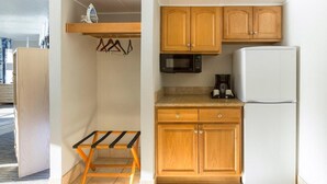 Une cuisine compacte avec des meubles en bois, un four à micro-ondes, un réfrigérateur blanc et une petite table.