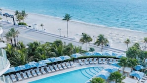 Un resort con piscina, playa y palmeras.
