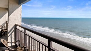 A balcony with a view of the ocean, wooden chairs, and a railing. - Penthouse Living Oceanfront Deluxe King Efficiency (Myrtle Beach)