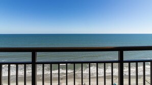 A beach view from a balcony with a railing.