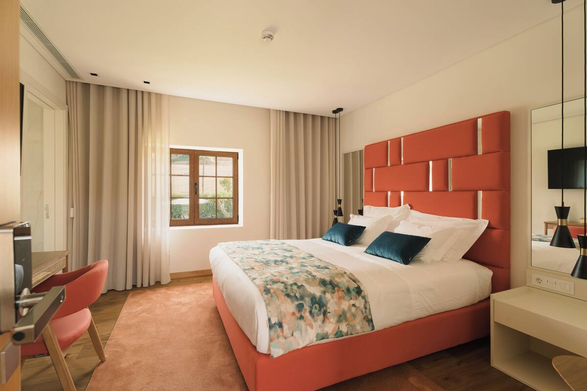 A modern hotel room with a large bed, a desk, and a television.