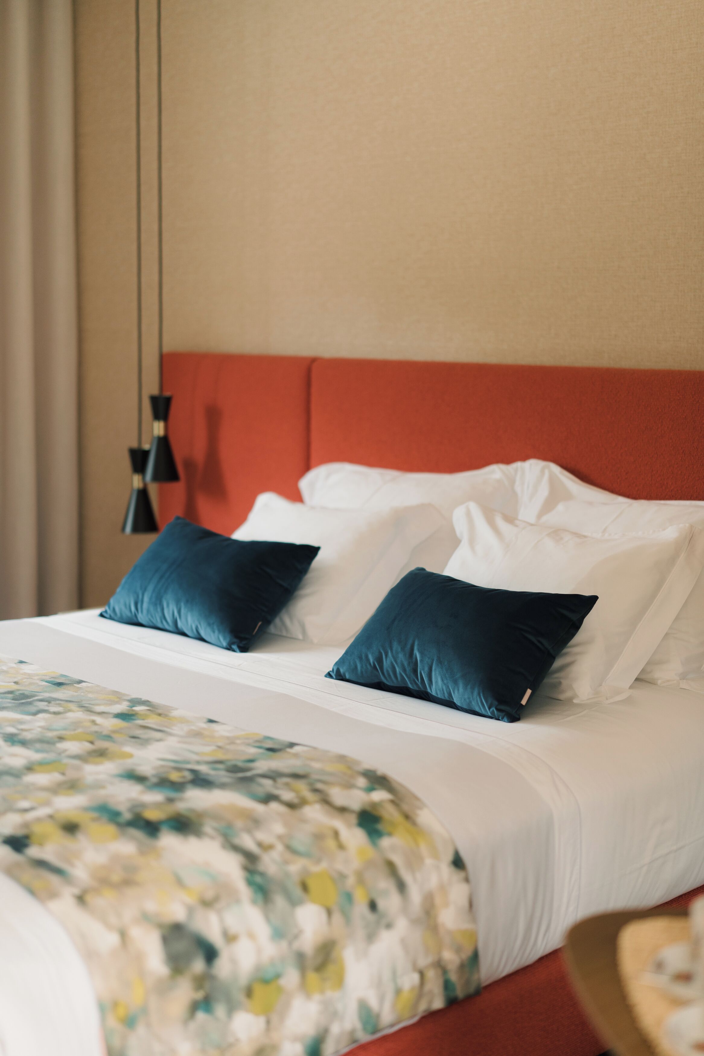 Une chambre d’hôtel avec un lit, des oreillers, une tête de lit et une lampe suspendue.