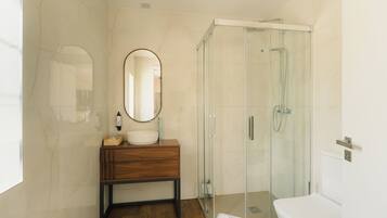 A modern bathroom with a glass shower enclosure, a wooden vanity, and a white sink.