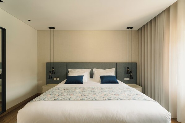 Una habitación de hotel moderna con una cama grande, dos mesitas de noche y un cabecero con iluminación integrada.