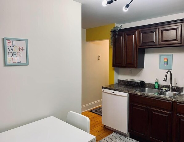 A compact kitchen with a dishwasher, a sink, and dark wooden cabinets.
