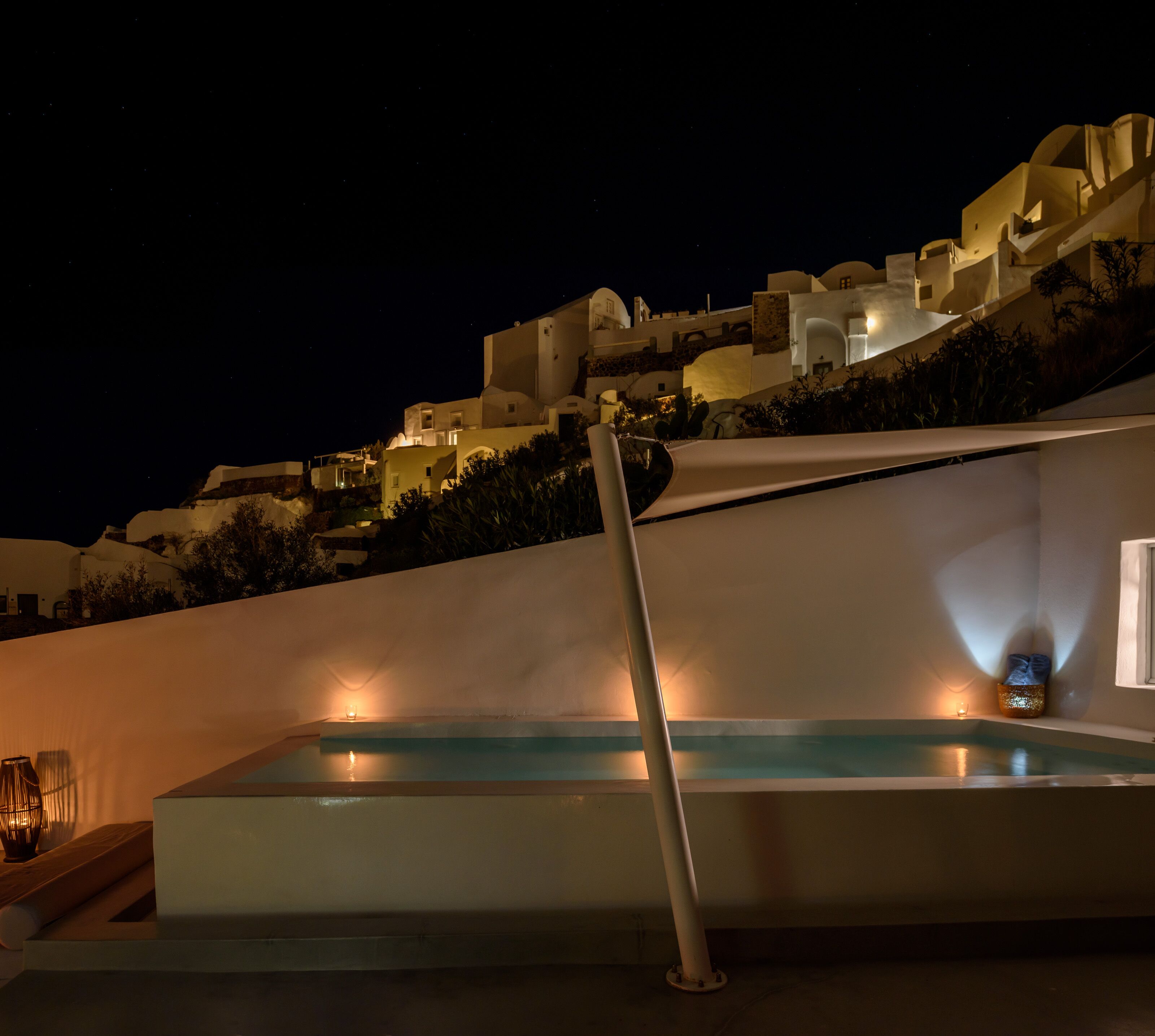Ein moderner Poolbereich im Freien mit Blick auf weißes Gebäude bei Nacht.