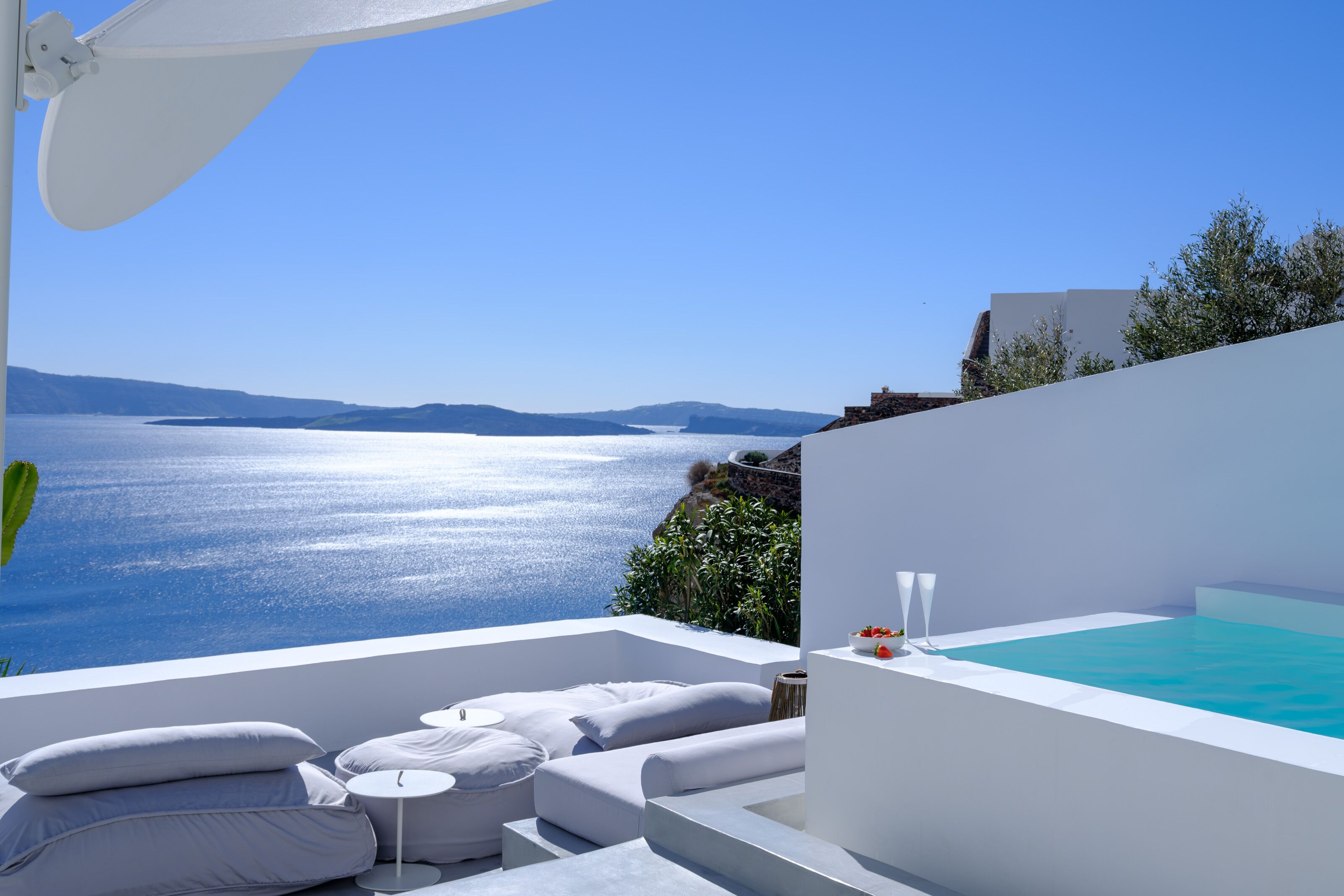 Un área de estar moderna al aire libre con vistas al mar, una piscina y un edificio blanco.