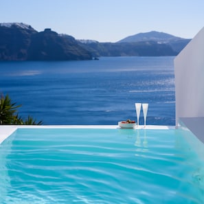 Ein klares, blaues Schwimmbecken mit Blick auf das Meer und ferne Berge.