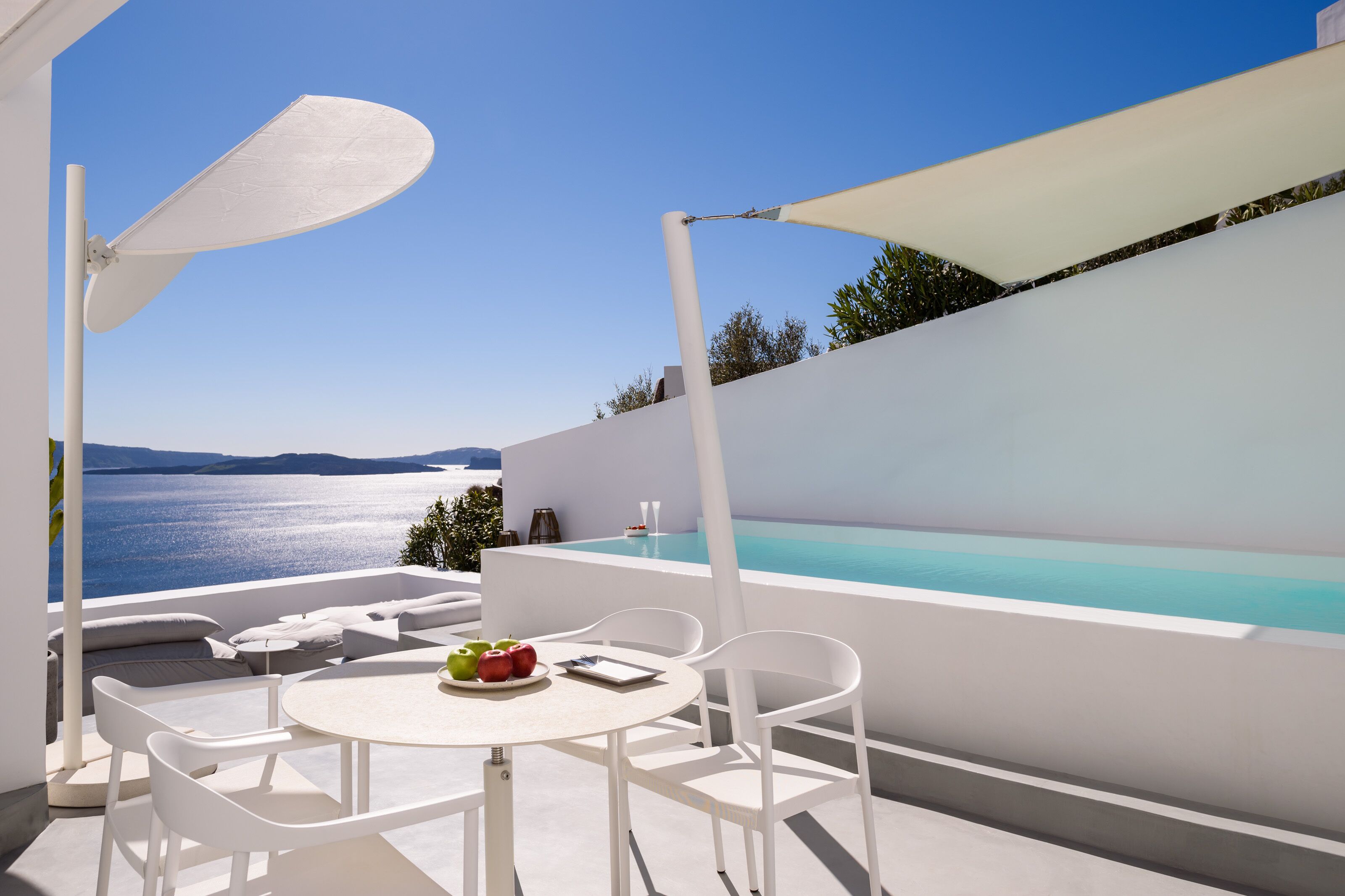 A modern outdoor seating area with a table, chairs, and a view of the sea.